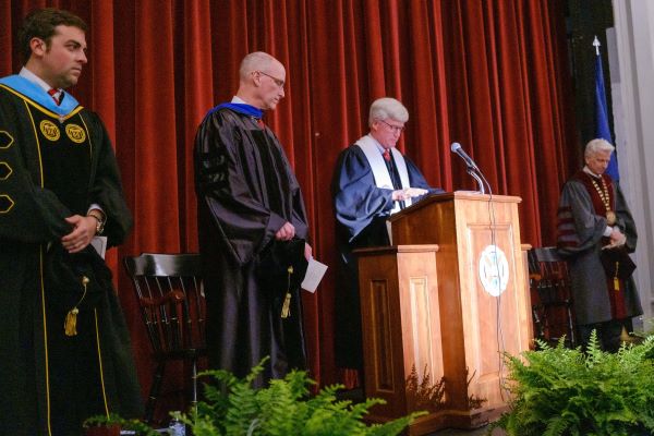 Administratiin in regalia standing on stage at the convocation ceremony