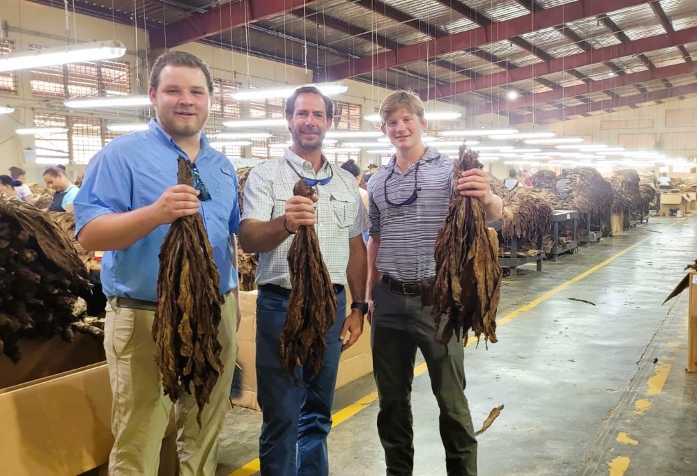 Students and alumnus standing in a tobacco warehouse