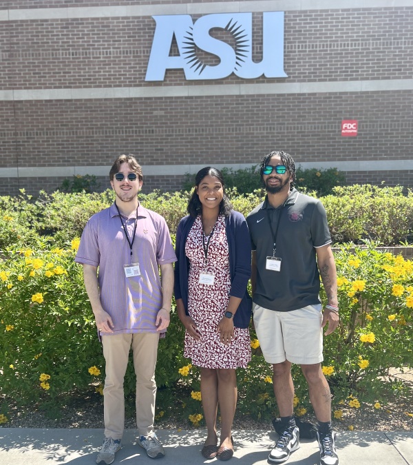 students and professor standing beside a "ASU" conference sign