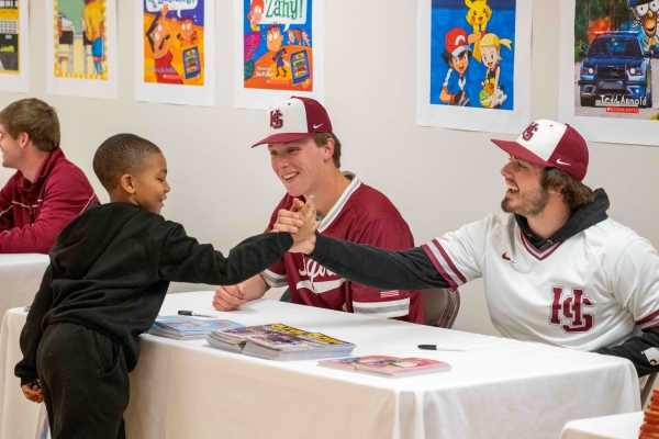 Hampden-Sydney students handing a book to a child