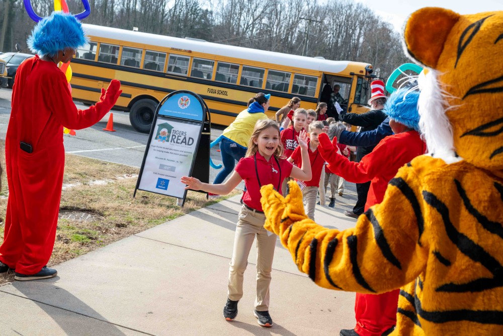 Children exiting a schoolbus and highfiving Dr. Seuss characters