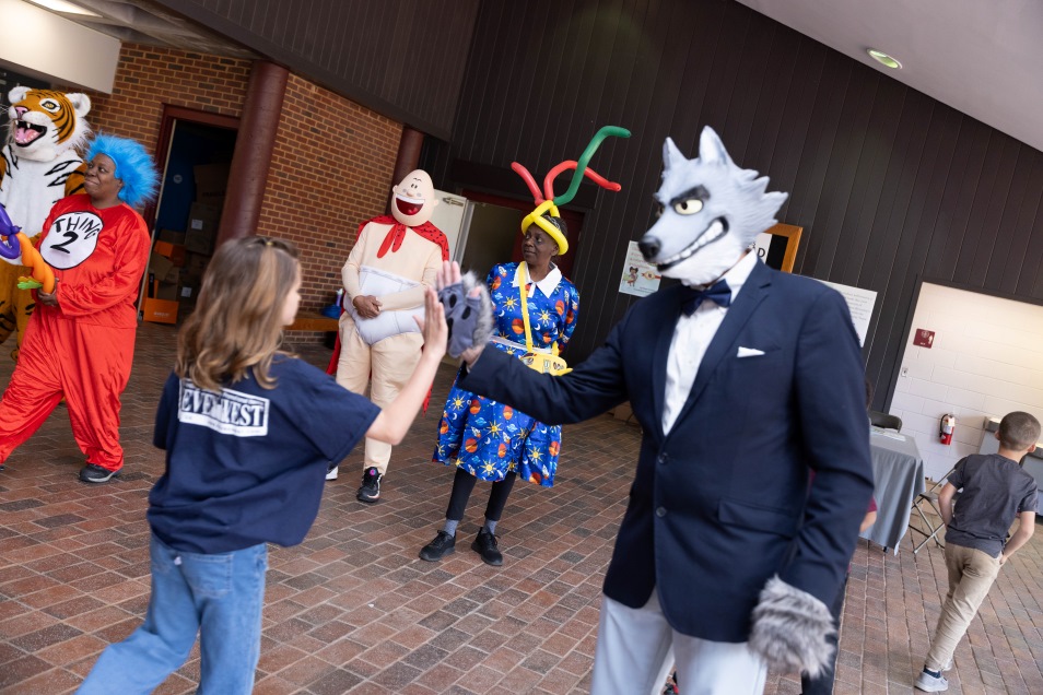 a wolf character high-fiving elementary students