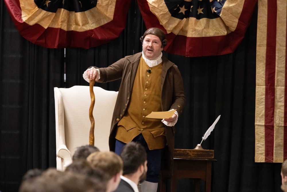 a reenactor dressed as an 18th century man delivering a speech