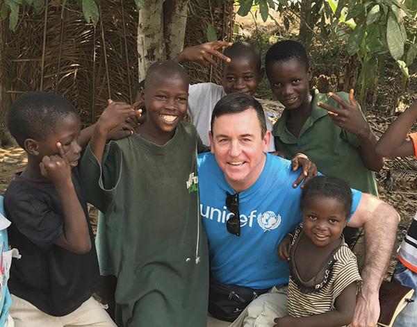 Barron Segar hugging a crowd of children in Africa