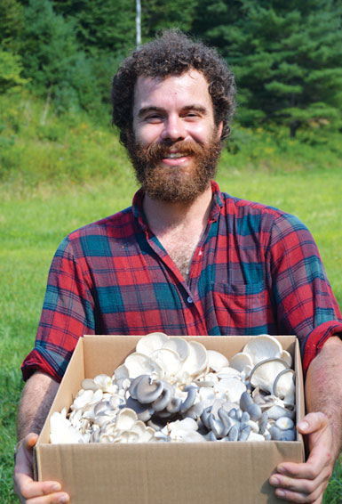 Matthew Reiss holding a box of mushroom harvest