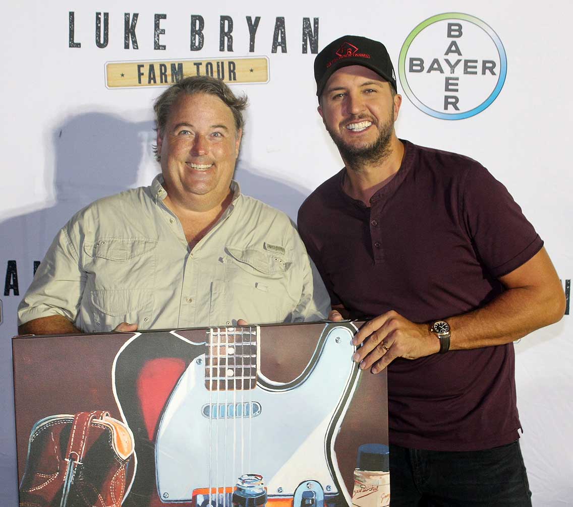 Christopher Mize and Luke Bryan holding a painting