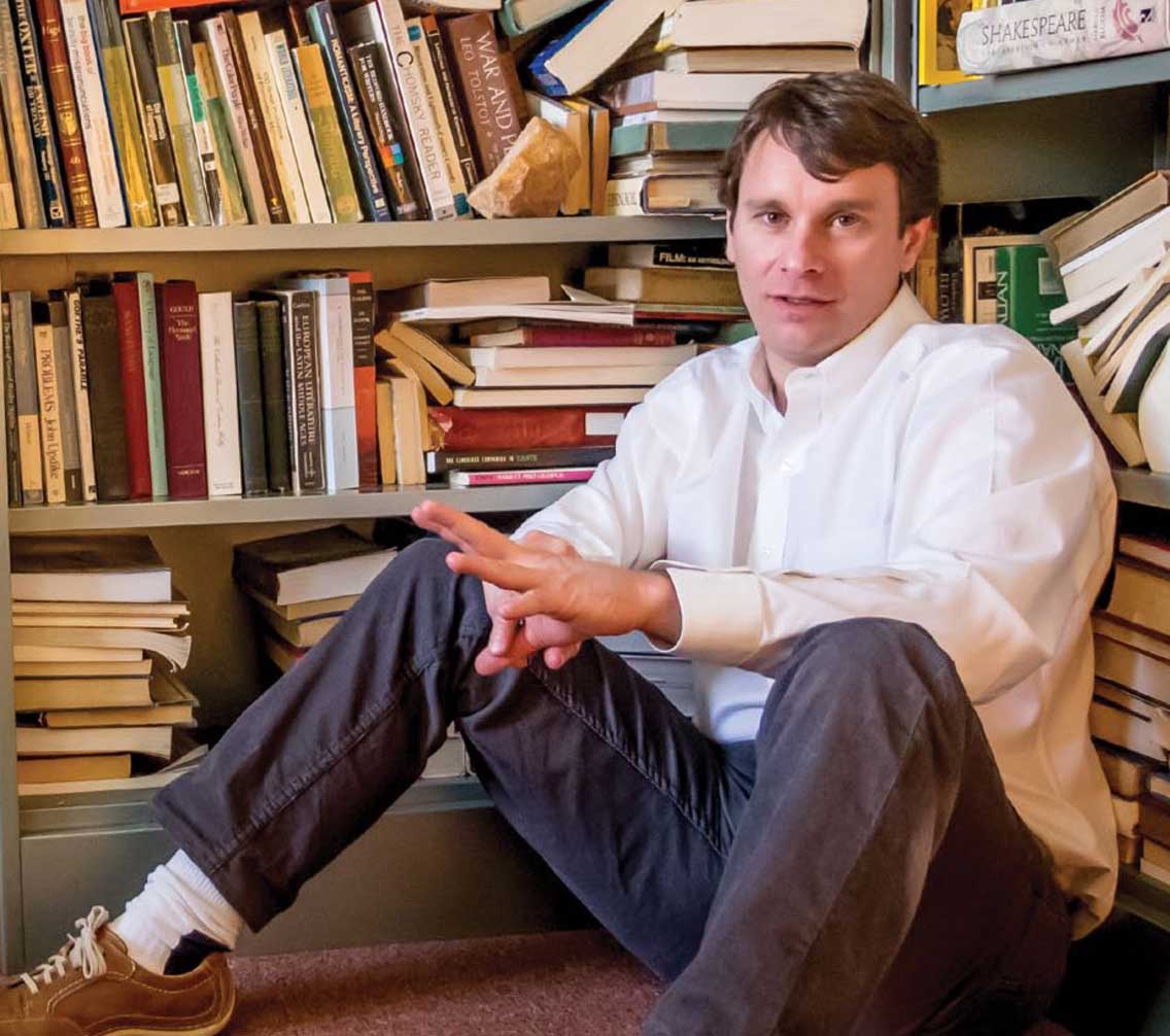 Dr. Rob Irons sitting among stacks of books