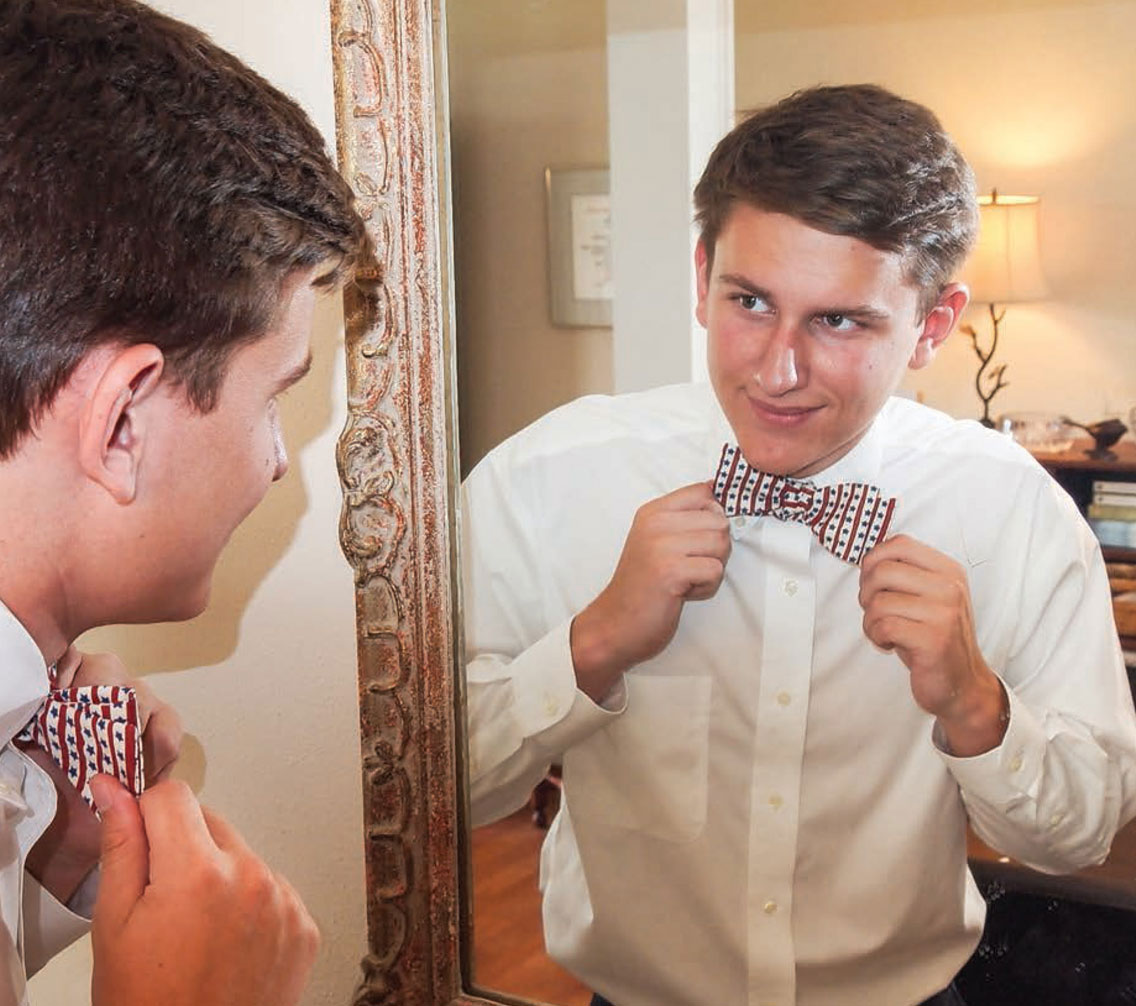 Rollie Edwards putting on a bowtie in the mirror