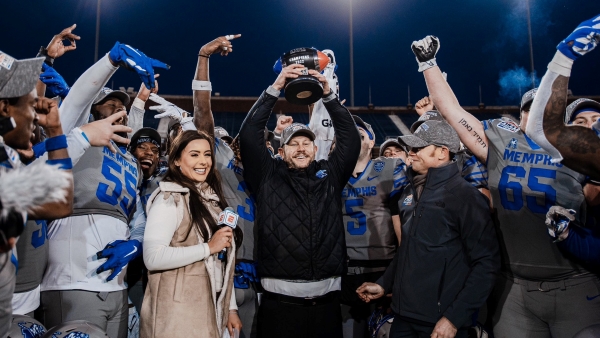 Coach Ryan Silverfield celebrating and holding a football winner's cup