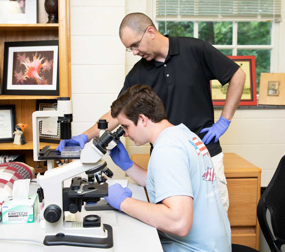 Corey Williams '19 and professor looking under a microscope