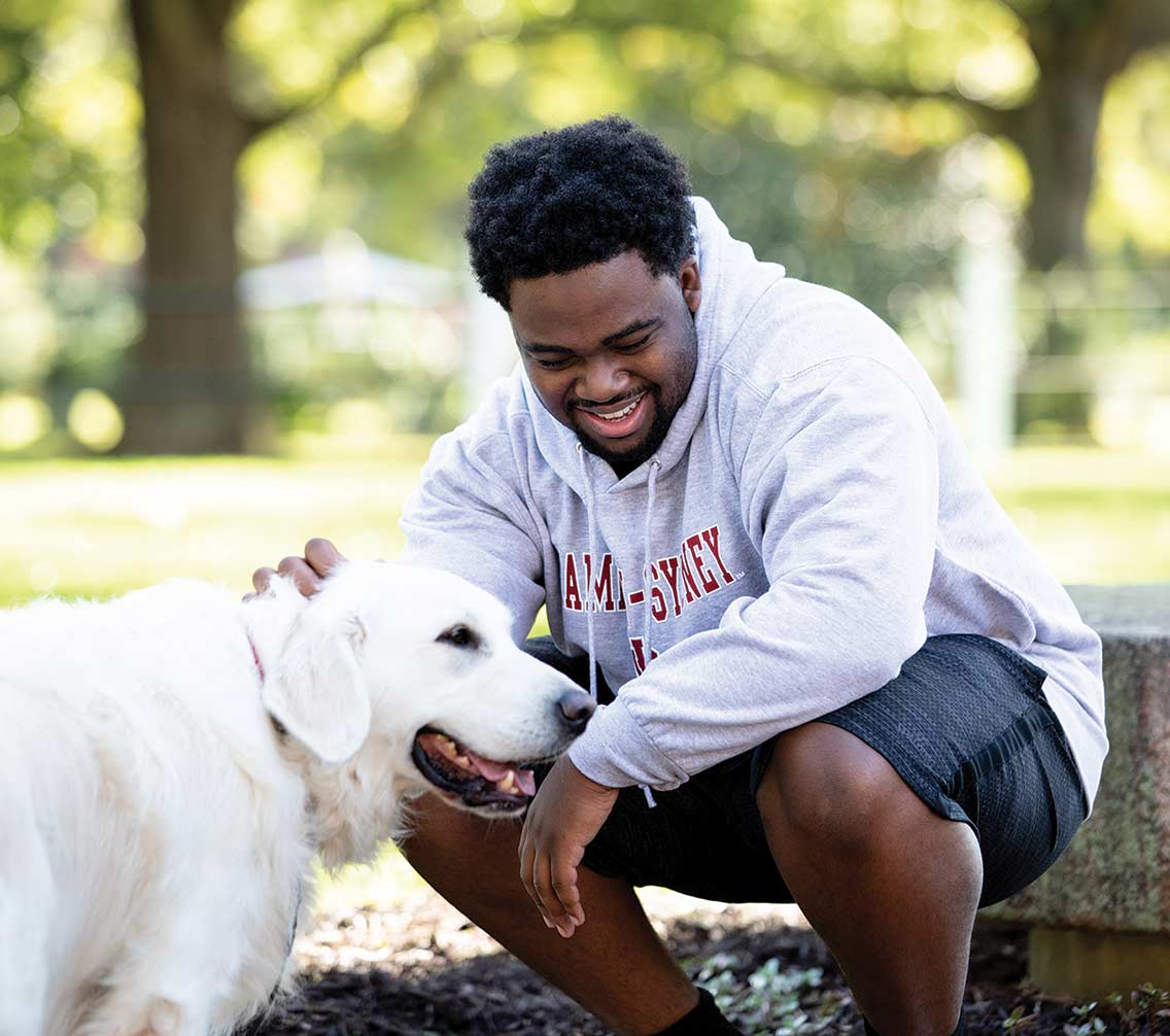 Student Jason Hill bends down to pet a dog.