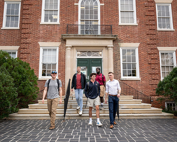 Students walking in front of a brick building talking and laughing