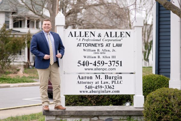 Grayson Manning standing in front of an Allen & Allen Firm sign