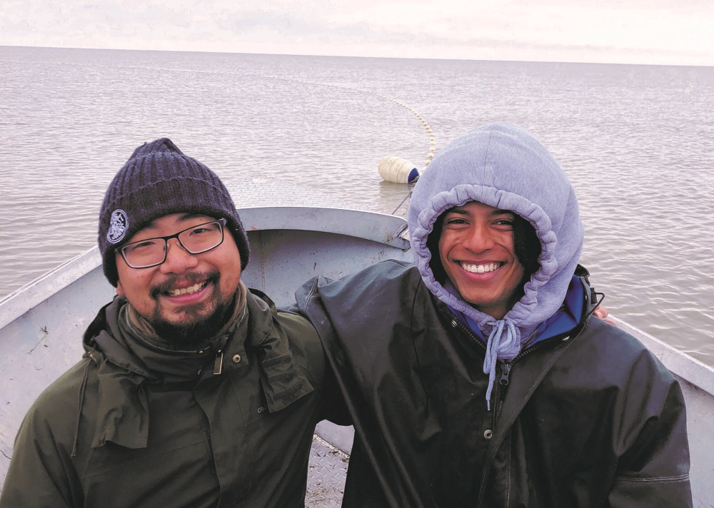 Izac Olatunji aboard a small boat with an Alaskan friend