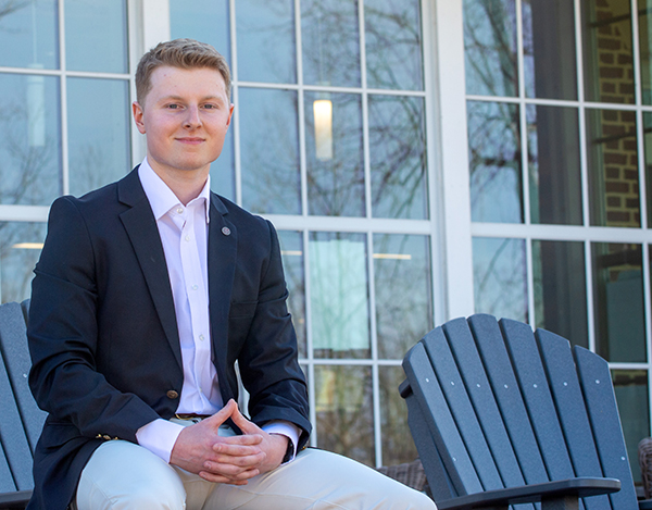 Noah Selfe '23 sitting in front of large windows