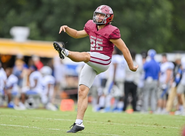 George Langhammer ’24 on the field kicking a football at a Tiger football game