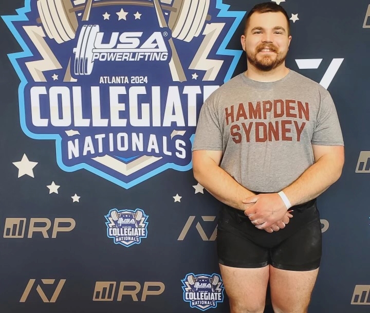 William Morris '25 standing in front of a Collegiate Nationals banner