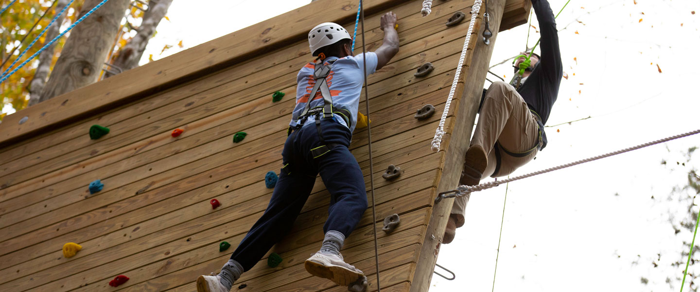 Studentys reaching for the top of the climbing wall at Hampden-Sydney College