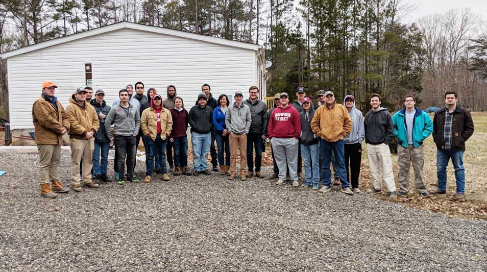 A large group of Hampden-Sydney College student volunteers standing in front of a Habitat for Humanity home