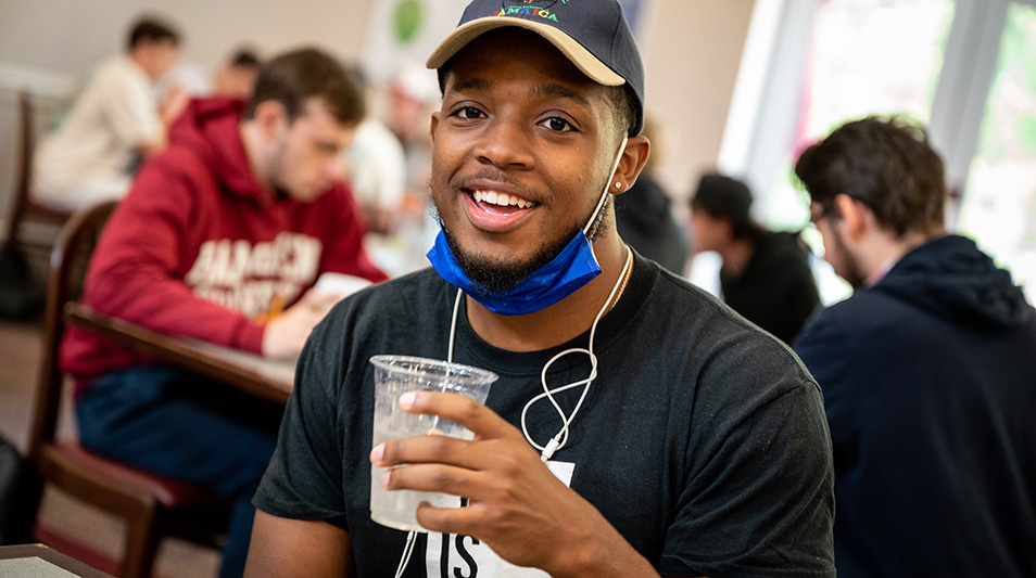 Student smiling and drinking in the dining hall