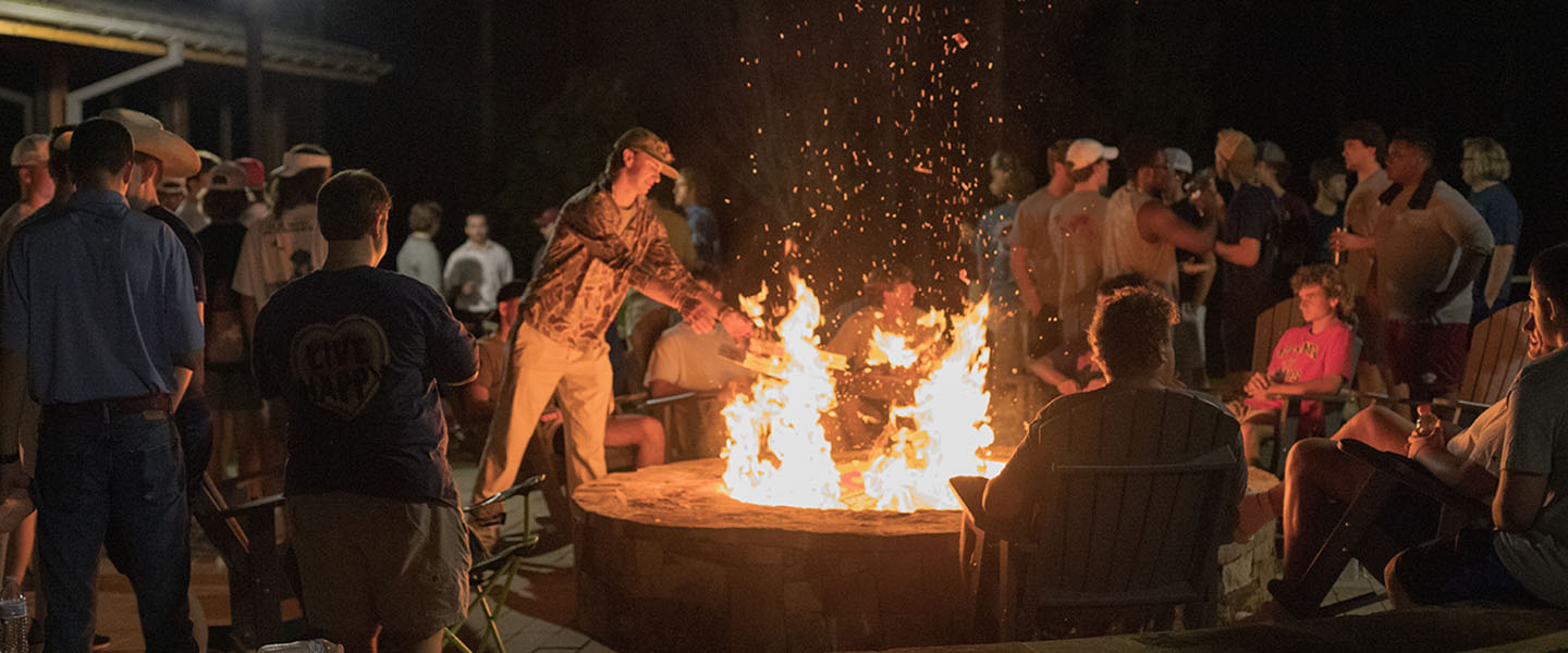 Friends sitting around a bonfire at night at Hampden-Sydney College 