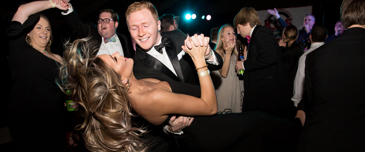 Students and their dates in formal attire dancing at a ball